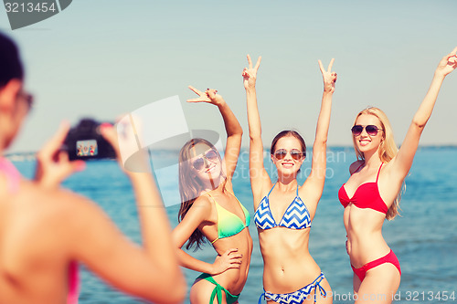 Image of group of smiling women photographing on beach