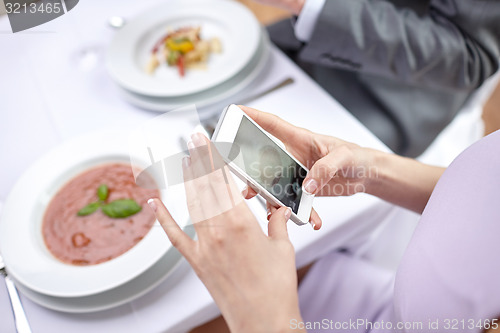 Image of close up of couple with smartphones at restaurant