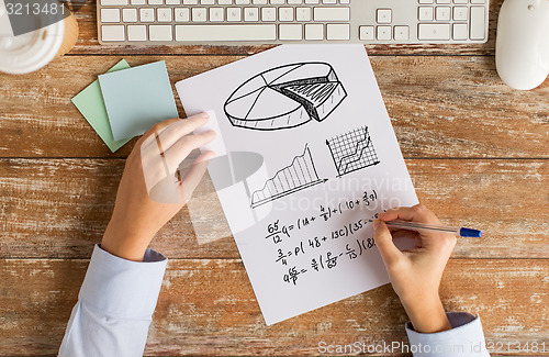 Image of close up of hands solving task or writing equation