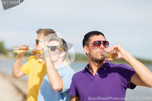 Image of happy friends with beer bottles on beach