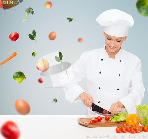 Image of smiling female chef chopping vegetables