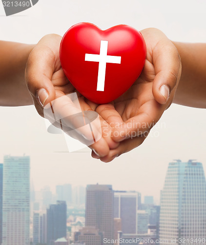 Image of close up of hands holding heart with cross symbol