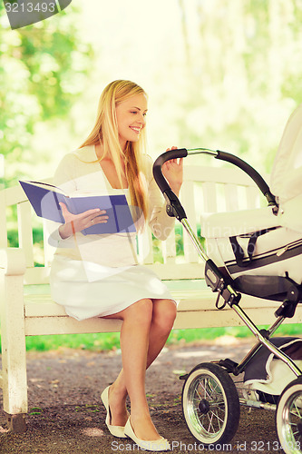 Image of happy mother with book and stroller in park