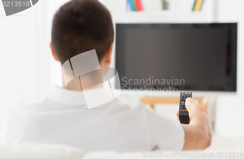 Image of man watching tv and changing channels at home