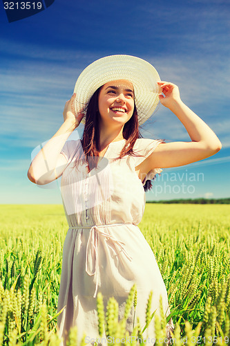 Image of smiling young woman in straw hat on cereal field