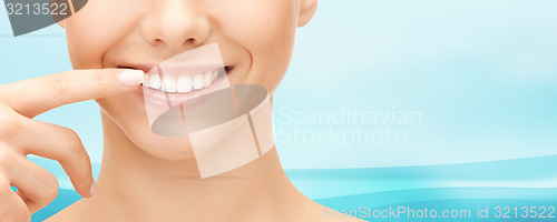 Image of close up of smiling woman face pointing to teeth