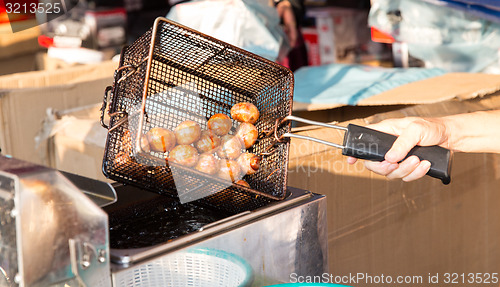 Image of close up of cook frying meatballs at street market