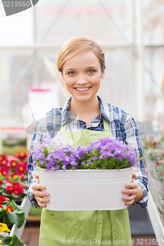 Image of happy woman holding flowers in greenhouse