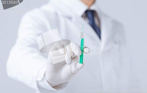 Image of male doctor holding syringe with injection