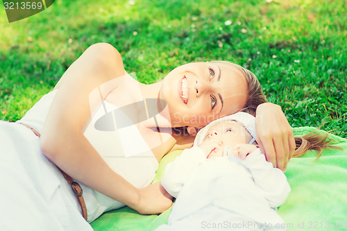 Image of happy mother lying with little baby on blanket