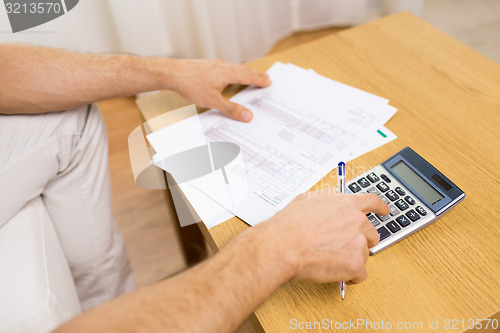 Image of close up of man with papers and calculator at home