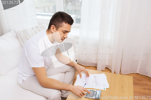 Image of man with papers and calculator at home