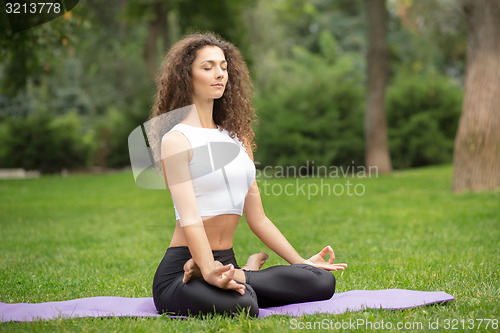 Image of Pretty woman doing yoga meditation in the lotus position