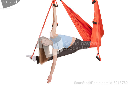 Image of Young woman doing anti-gravity aerial yoga in hammock on a seamless white background.