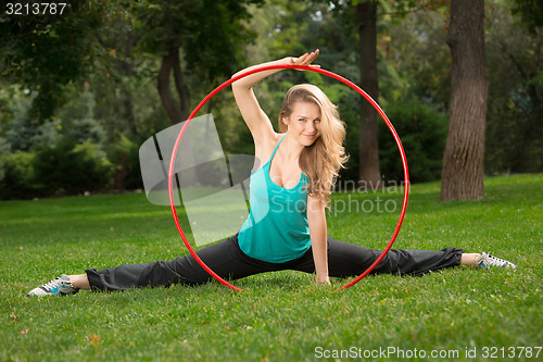 Image of Young female athlete holding a hula hoop in the park