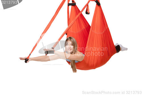 Image of Young woman doing anti-gravity aerial yoga in hammock on a seamless white background.