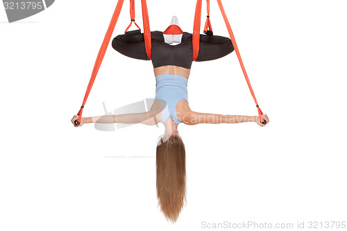 Image of Young woman doing anti-gravity aerial yoga in hammock on a seamless white background.