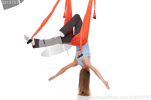 Image of Young woman doing anti-gravity aerial yoga in hammock on a seamless white background.