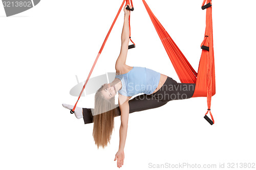 Image of Young woman doing anti-gravity aerial yoga in hammock on a seamless white background.