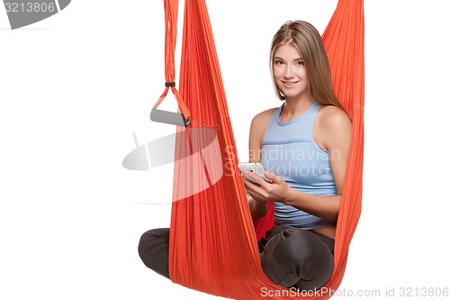 Image of Young woman sitting in hammock for anti-gravity aerial yoga