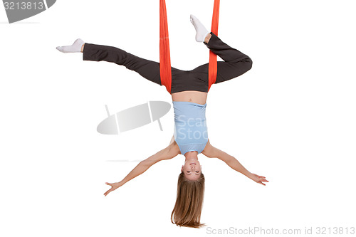 Image of Young woman doing anti-gravity aerial yoga in hammock on a seamless white background.