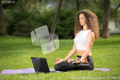 Image of Meditating woman with laptop