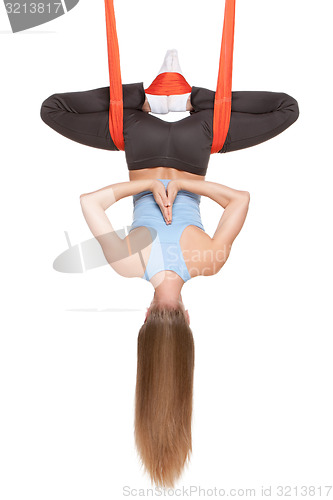 Image of Young woman doing anti-gravity aerial yoga in hammock on a seamless white background.