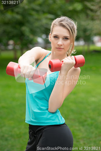 Image of Sports girl exercise with  dumbbells in the park
