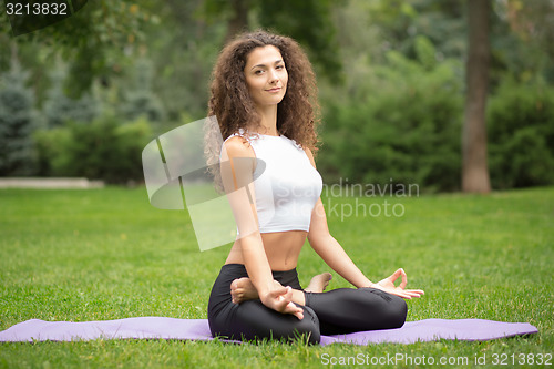 Image of Pretty woman doing yoga meditation in the lotus position