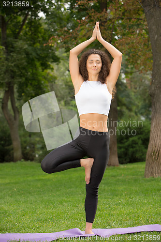 Image of Smiling pretty woman doing yoga exercises