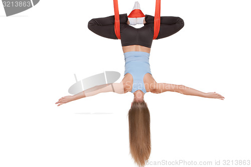 Image of Young woman doing anti-gravity aerial yoga in hammock on a seamless white background.