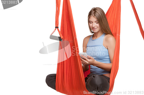 Image of Young woman sitting in hammock for anti-gravity aerial yoga