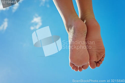 Image of Children\'s feet with sand against the blue sky