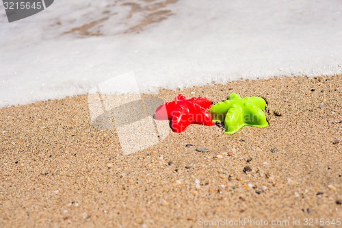 Image of Red and green starfish-shaped molds on the sand