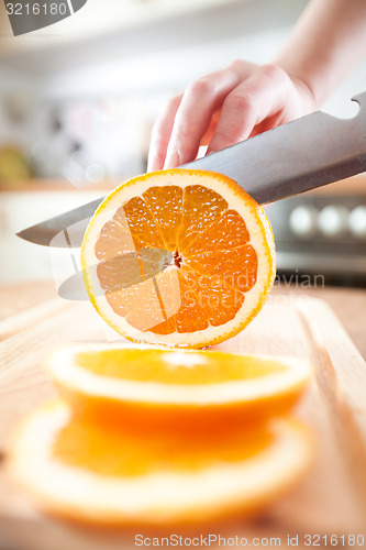 Image of Woman\'s hands cutting orange