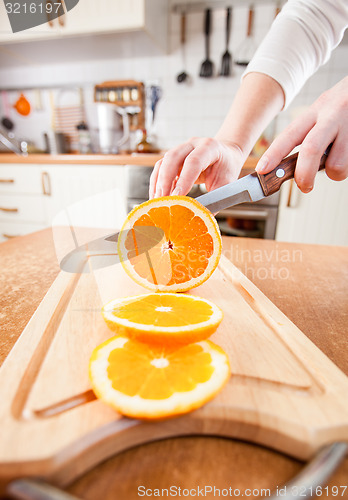 Image of Woman\'s hands cutting orange