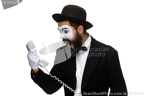 Image of angry and irritated  man screams into the telephone receiver 