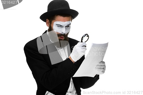 Image of Man with a face mime reading through magnifying glass 