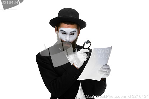 Image of Man with a face mime reading through magnifying glass 