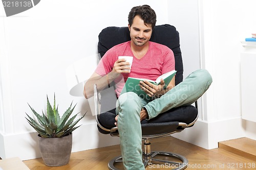 Image of Man Sitting on Chair with Book and a Drink