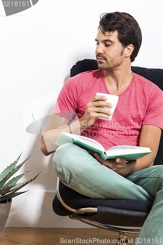 Image of Man Sitting on Chair with Book and a Drink