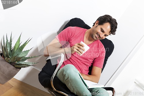 Image of Man Sitting on Chair with Book and a Drink