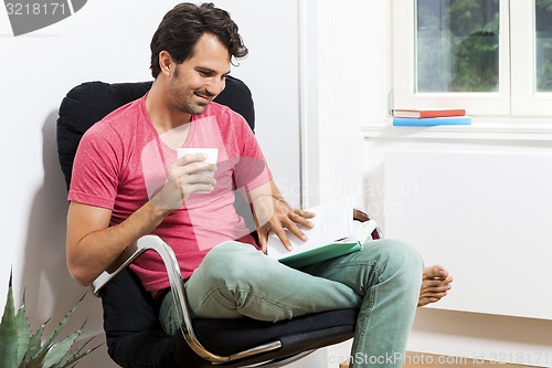 Image of Man Sitting on Chair with Book and a Drink