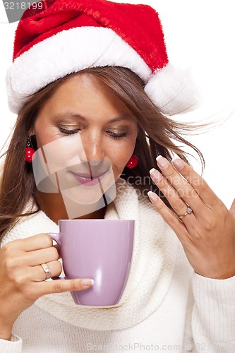 Image of Cold young woman in a Santa hat sipping coffee tea