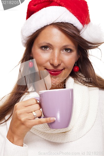 Image of Cold young woman in a Santa hat sipping coffee tea