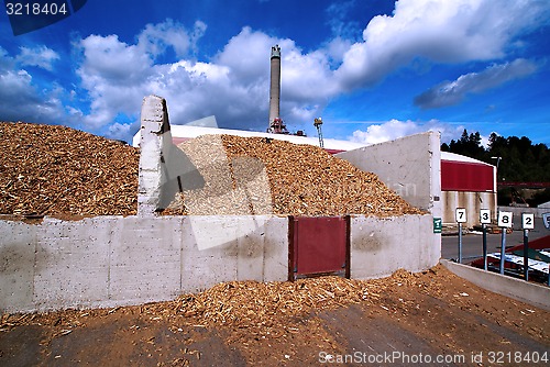 Image of bio power plant with storage of wooden fuel against blue sky