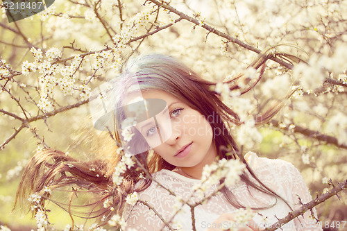 Image of Portrait of cheerful fashionable woman in spring blooming tree