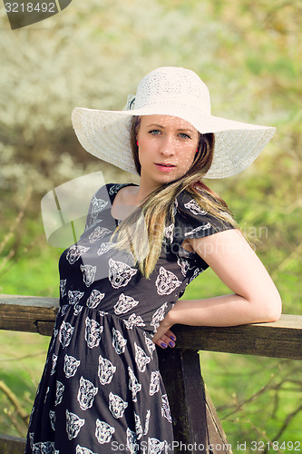 Image of Cheerful fashionable woman in stylish hat and frock posing