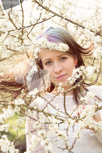Image of Portrait of cheerful fashionable woman in spring blooming tree