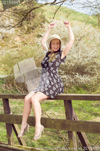 Image of Cheerful fashionable woman in stylish hat and frock posing